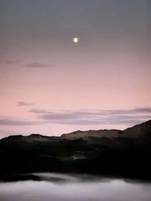 moon rising over a lake with fog